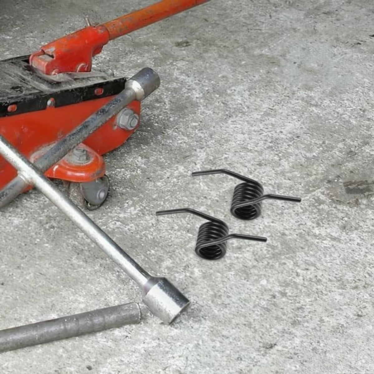 Black steel hydraulic jack handle spring coils with straight ends, on concrete.