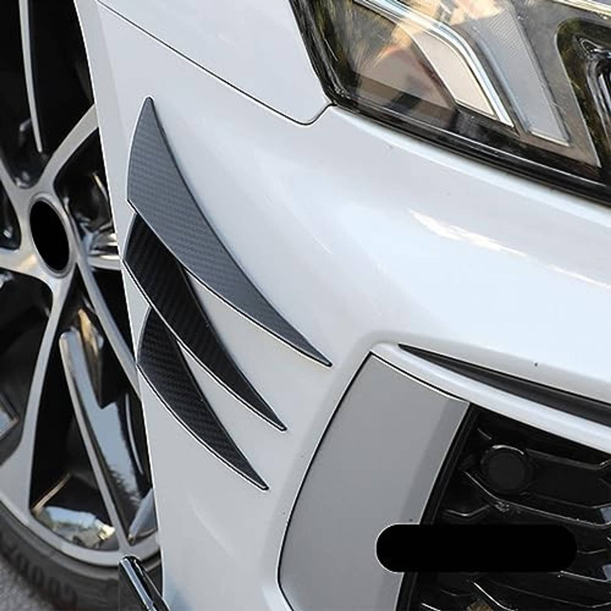 Carbon-fiber-look black front bumper canards mounted on a white car