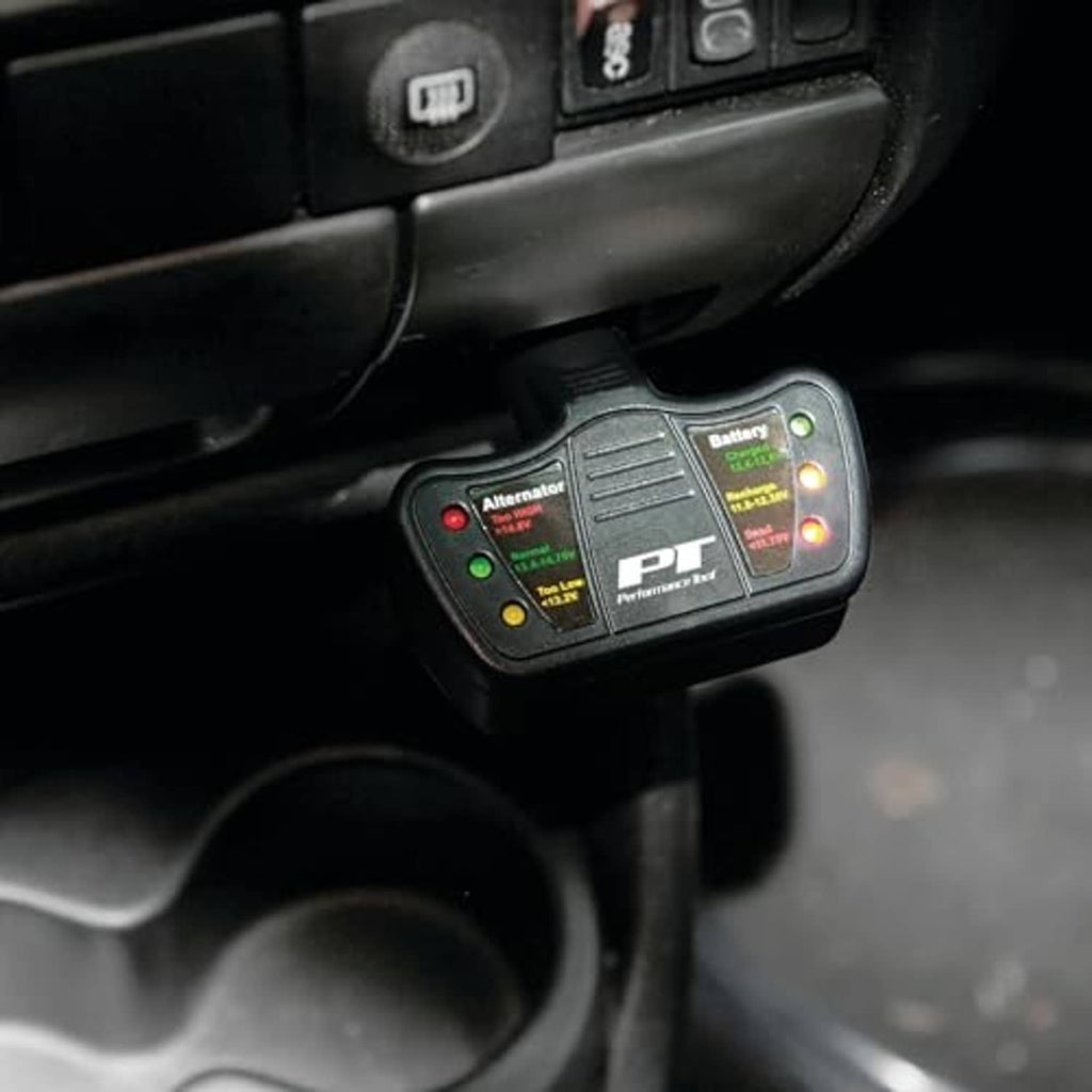 Black battery and alternator tester plugged into a car dashboard port with LEDs