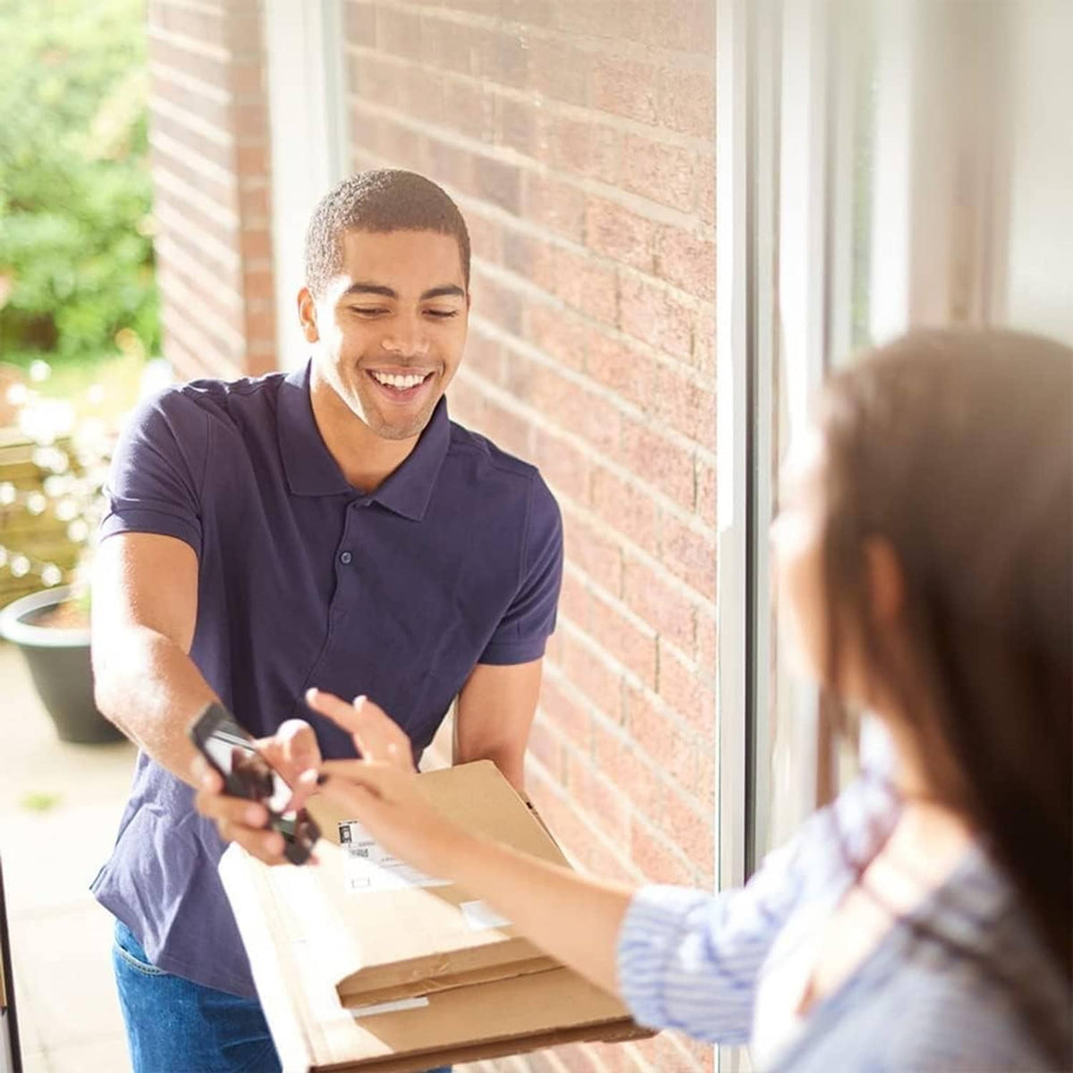 Small cardboard shipping box being delivered at the door, held in both hands