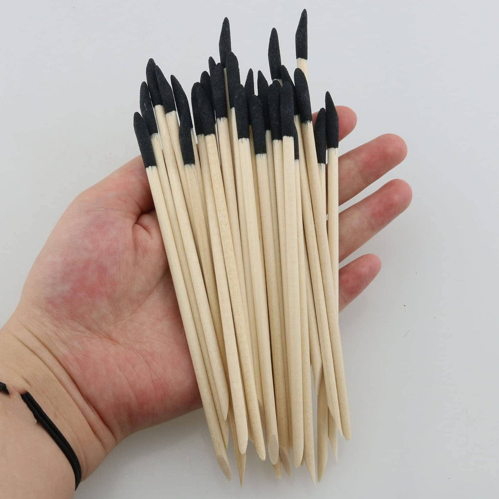 Bundle of sanding sticks held in hand: pale wood with black slanted abrasive tips