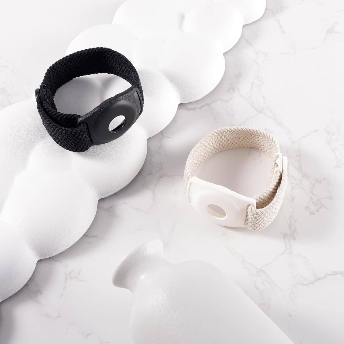 Braided medallion holder bracelets, black and beige on light marble surface
