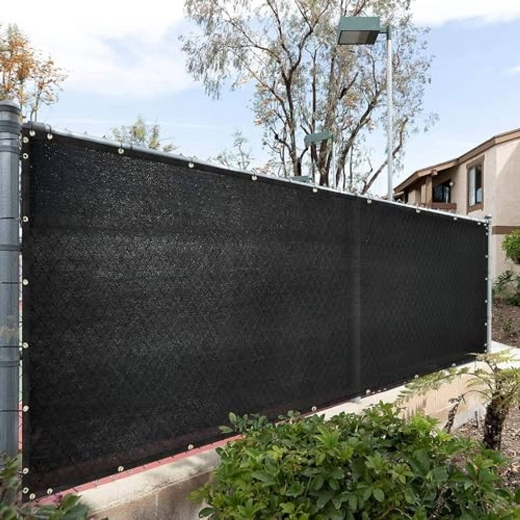 Dark mesh shade cloth panel attached along a fence line with metal grommets