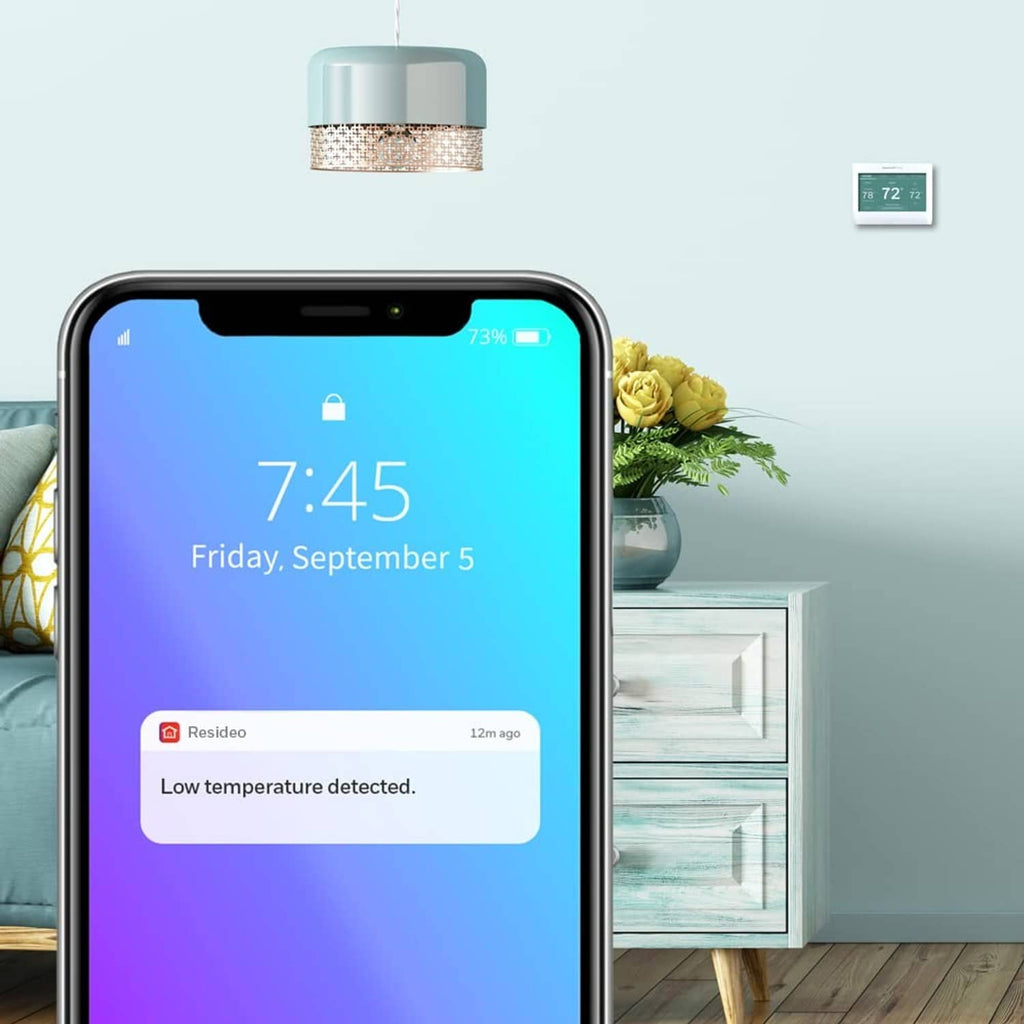 Smartphone showing a temperature alert screen with a small smart color thermostat display.