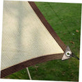 Beige outdoor sunshade cloth with dark trim and metal corner clip on green grass