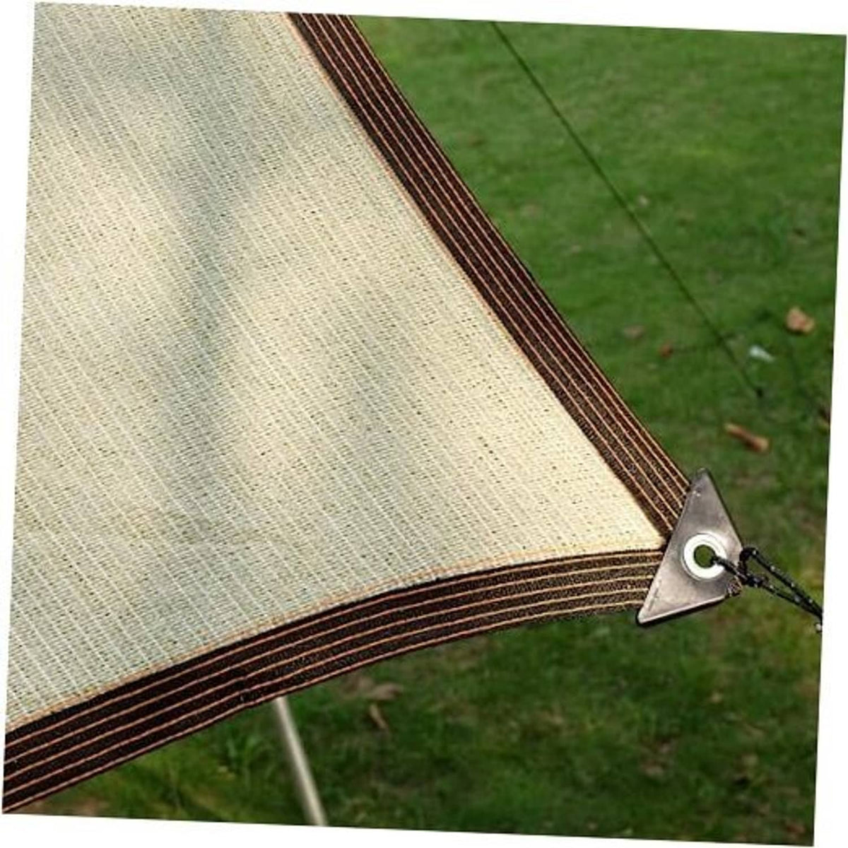 Beige outdoor sunshade cloth with dark trim and metal corner clip on green grass