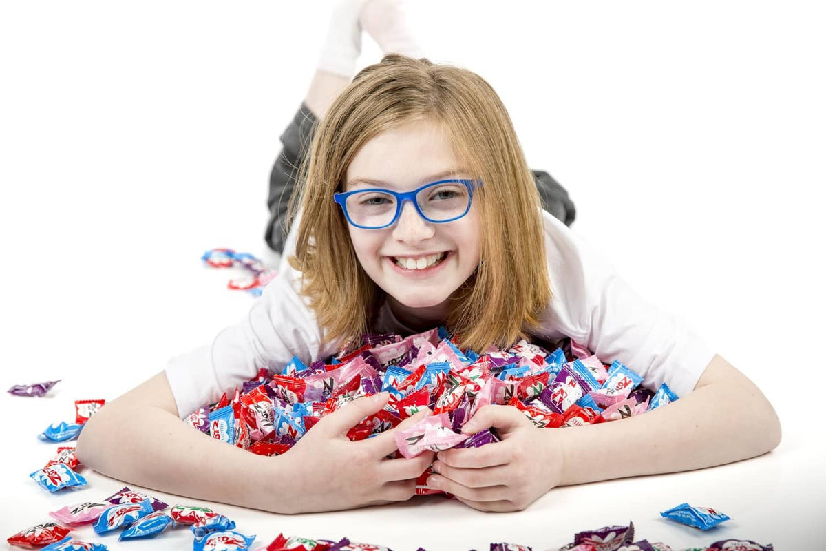 Child holding a pile of assorted Zotz fizzy hard candy, individually wrapped pieces