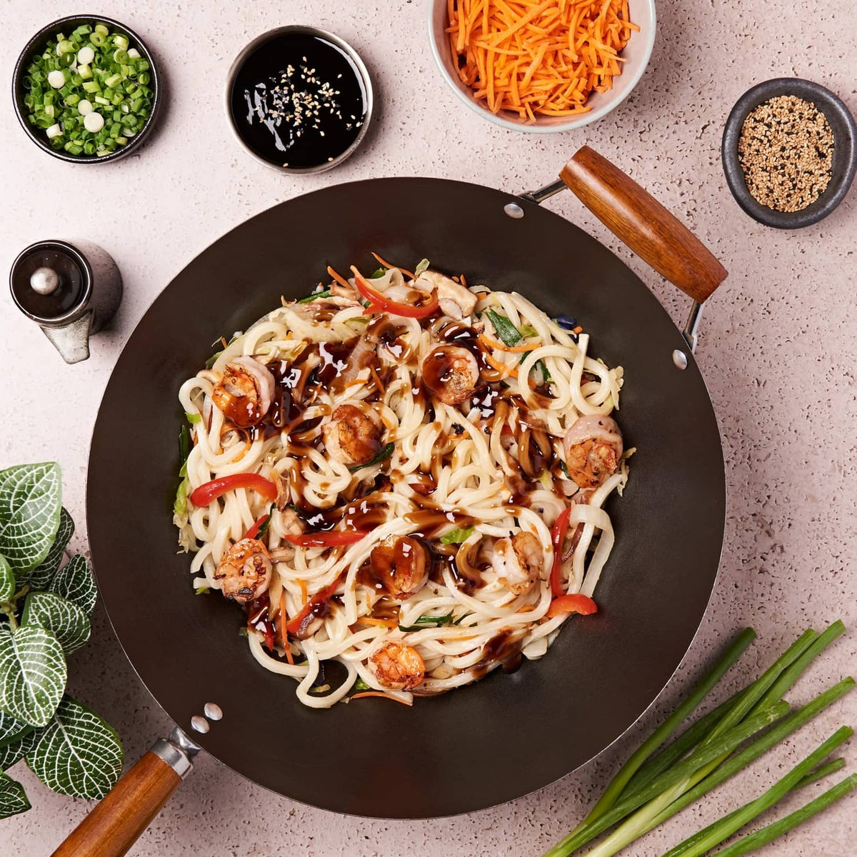Noodles with dark oyster-sauce glaze in a skillet with garnishes