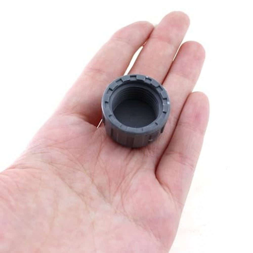 Grey PVC threaded cap plug adapter in hand, open end with internal threads
