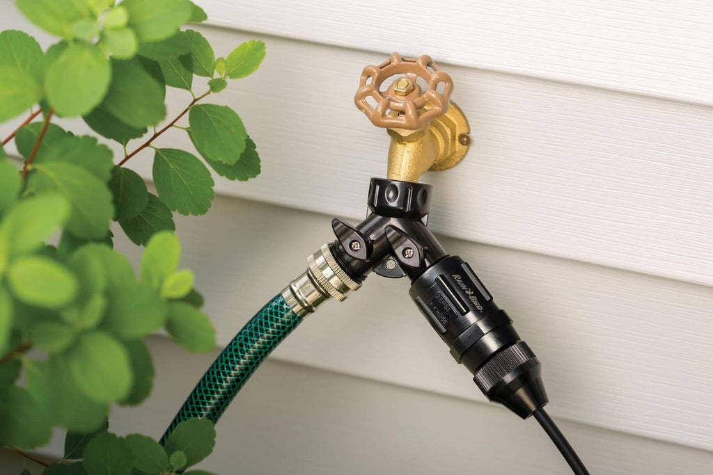 Rain Bird pressure regulator with brass valve and green mesh hose on siding