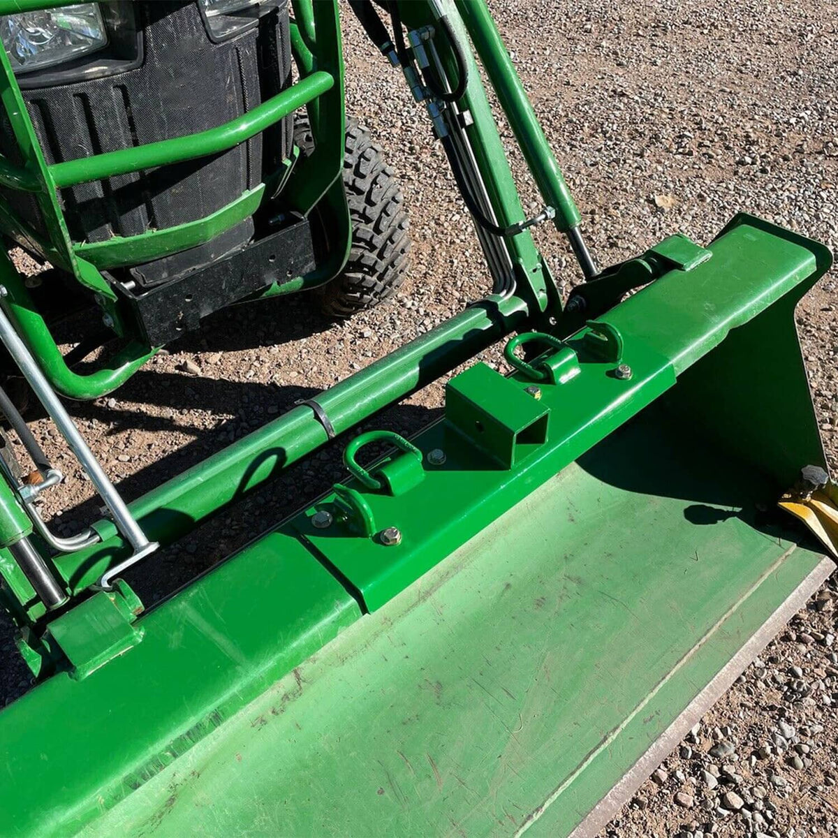 Green grab hook receiver bracket with two D-ring hooks mounted on a tractor