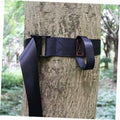 Navy nylon tree strap with buckle and tie loop, secured around a tree trunk