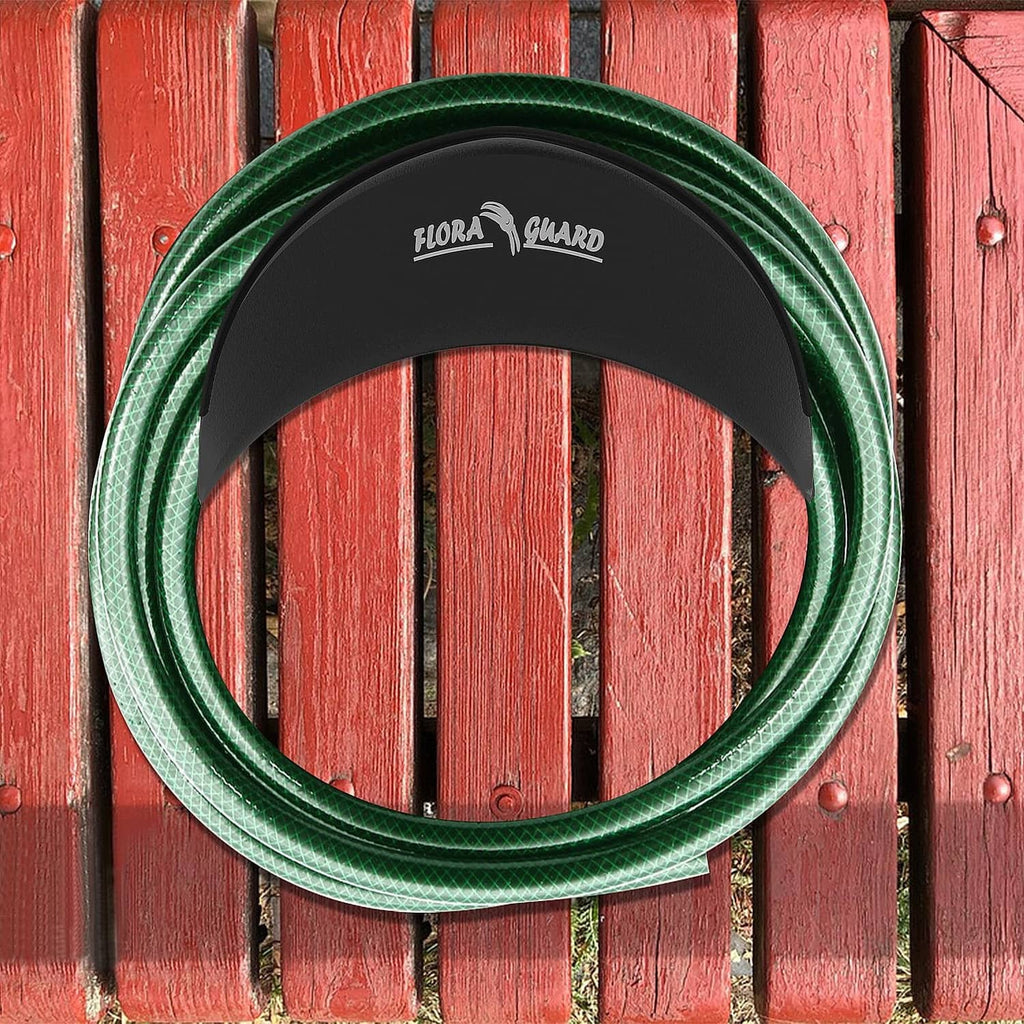 Black hose hanger holding a coiled green garden hose on a wooden fence