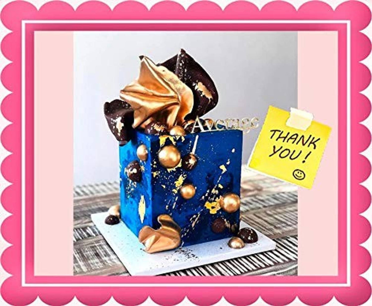 Blue cake topped with gold sprinkles, dark chocolate pieces, and gold foil