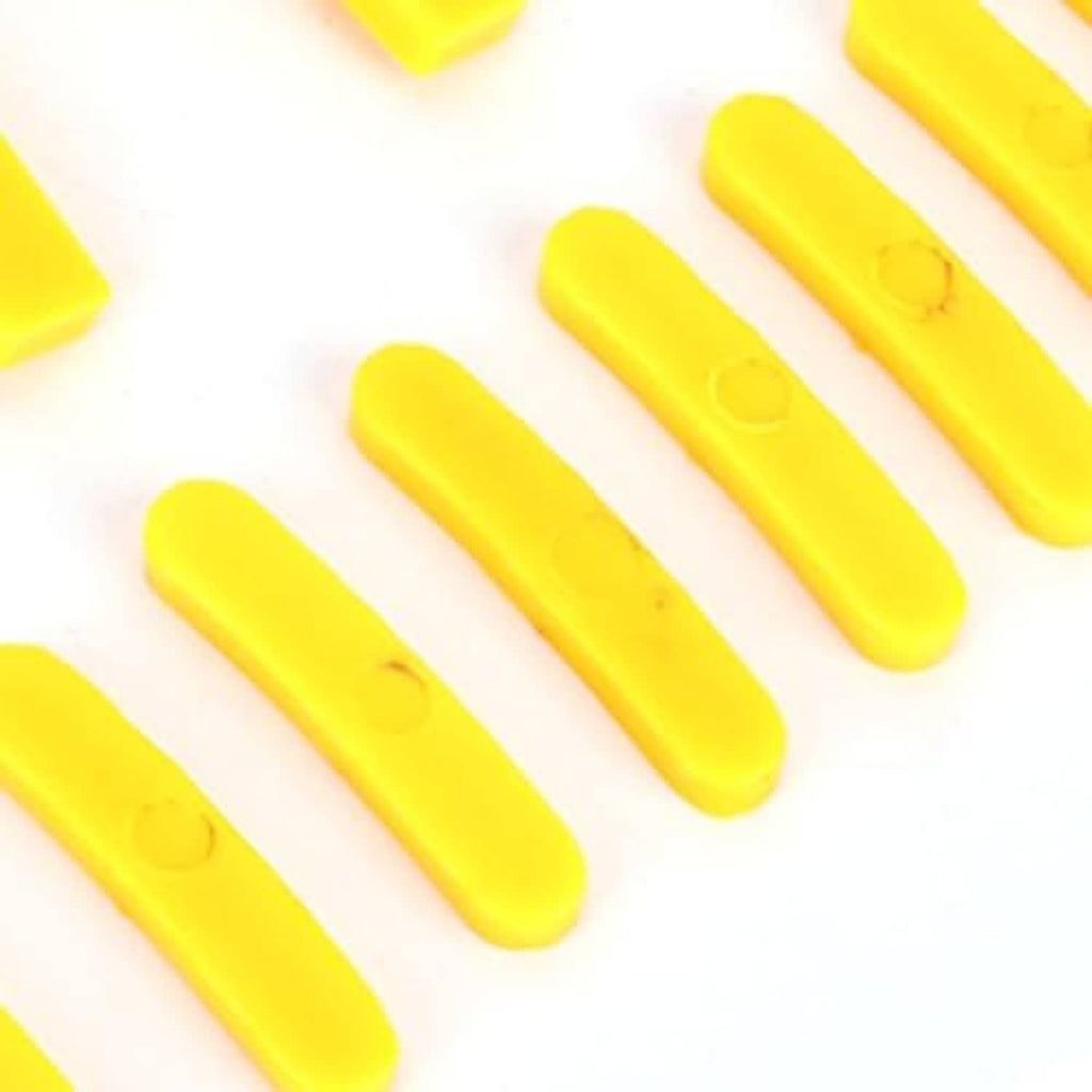 Yellow tire changer protector strip pieces, molded plastic, laid on white