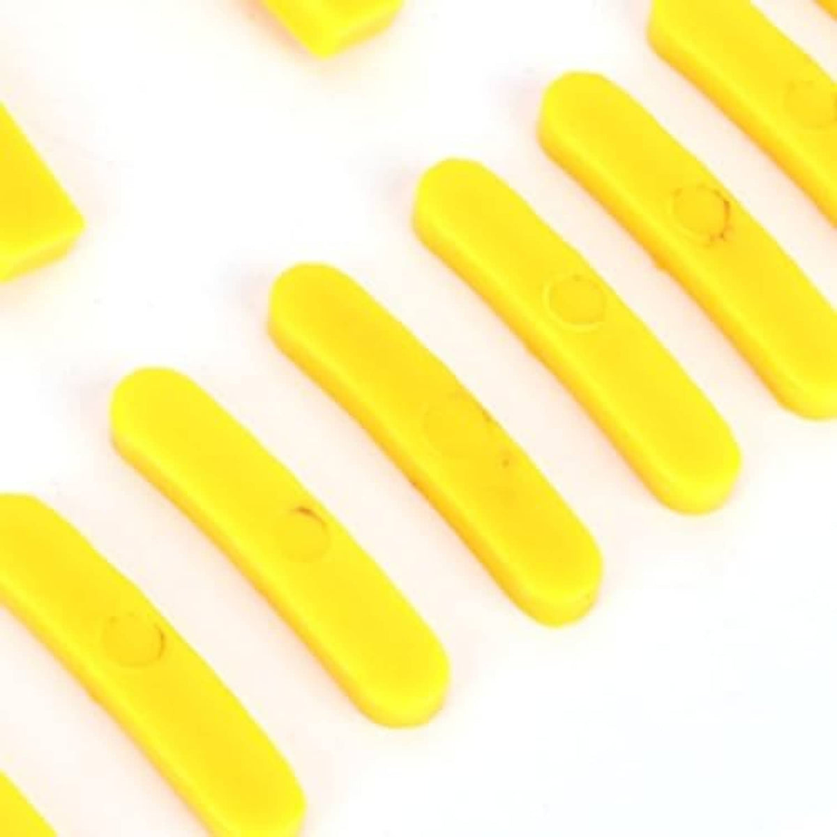Yellow tire changer protector strip pieces, molded plastic, laid on white