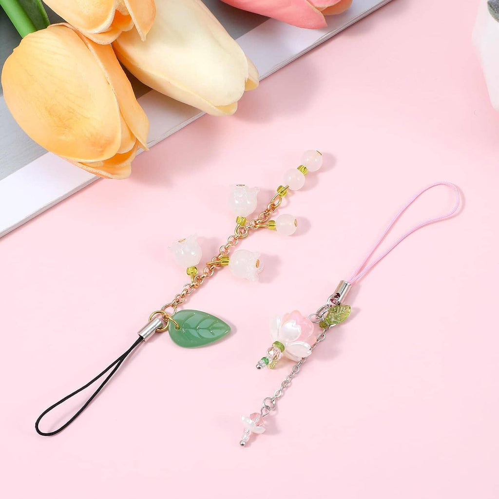 Two phone charm lanyards laid flat with green leaf, pink flower, and crystal bead charms