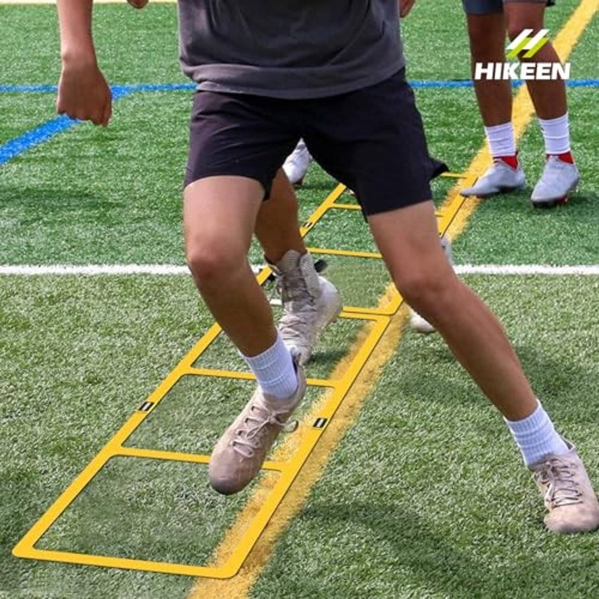 Yellow speed ladder on grass with shoes stepping through rectangular rungs