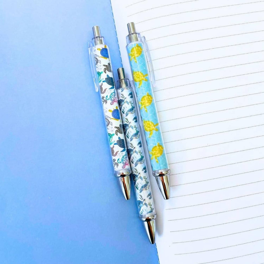 Two turtle-print pens with clear barrels and silver tips with yellow turtles