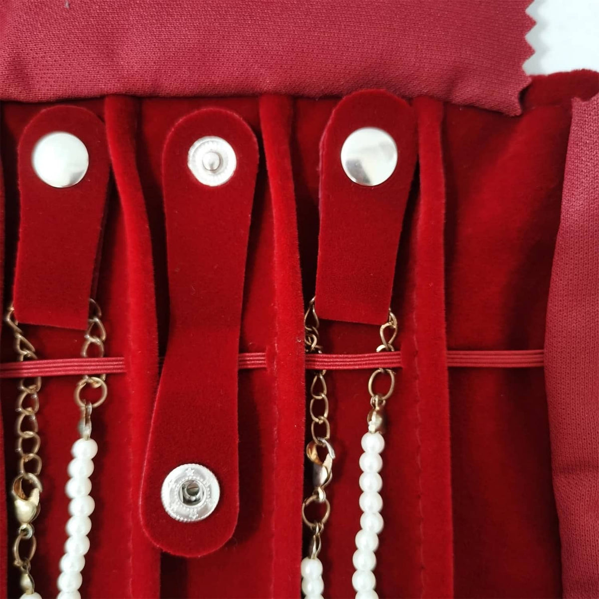 Close-up of burgundy necklace roll with snap studs and pearl bead necklace loops