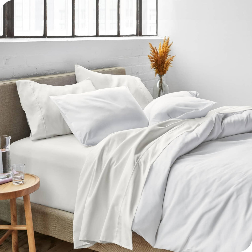 Cream bed sheet set on a sofa bed with pillows and neatly folded bedding