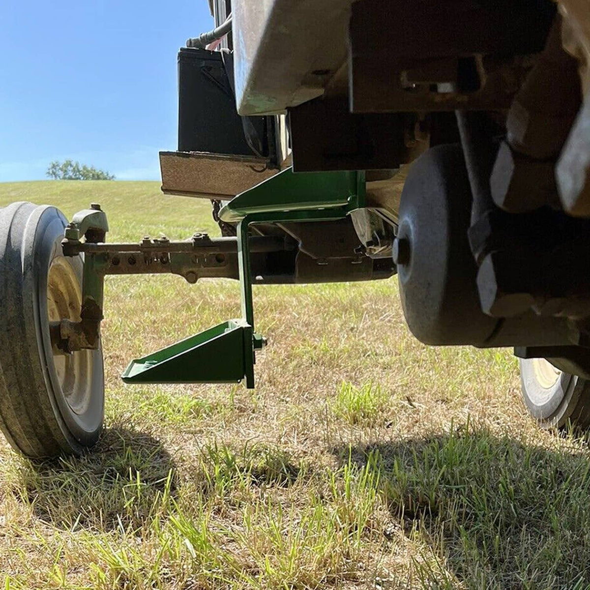 Green tractor side step mounted under chassis with perforated foot platform