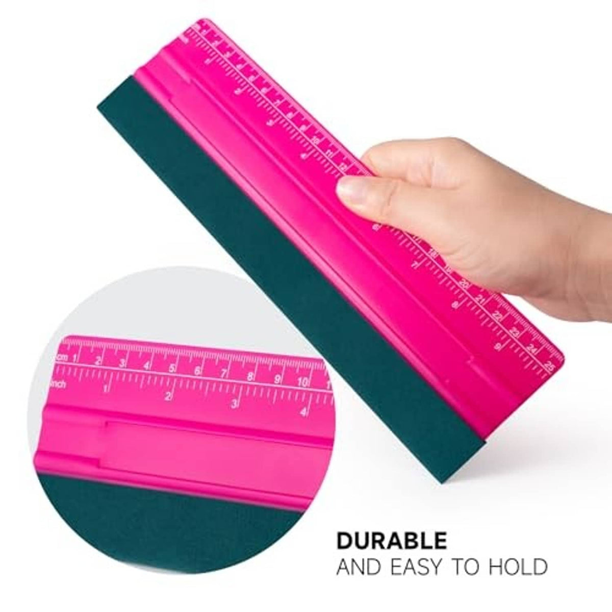 Pink squeegee with teal felt pad and ruler scale, held in hand for smooth application