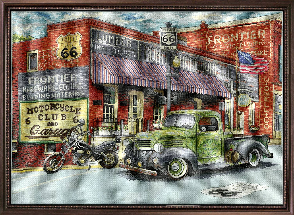 Framed cross-stitch finished picture with vintage green truck, motorcycle, and storefront