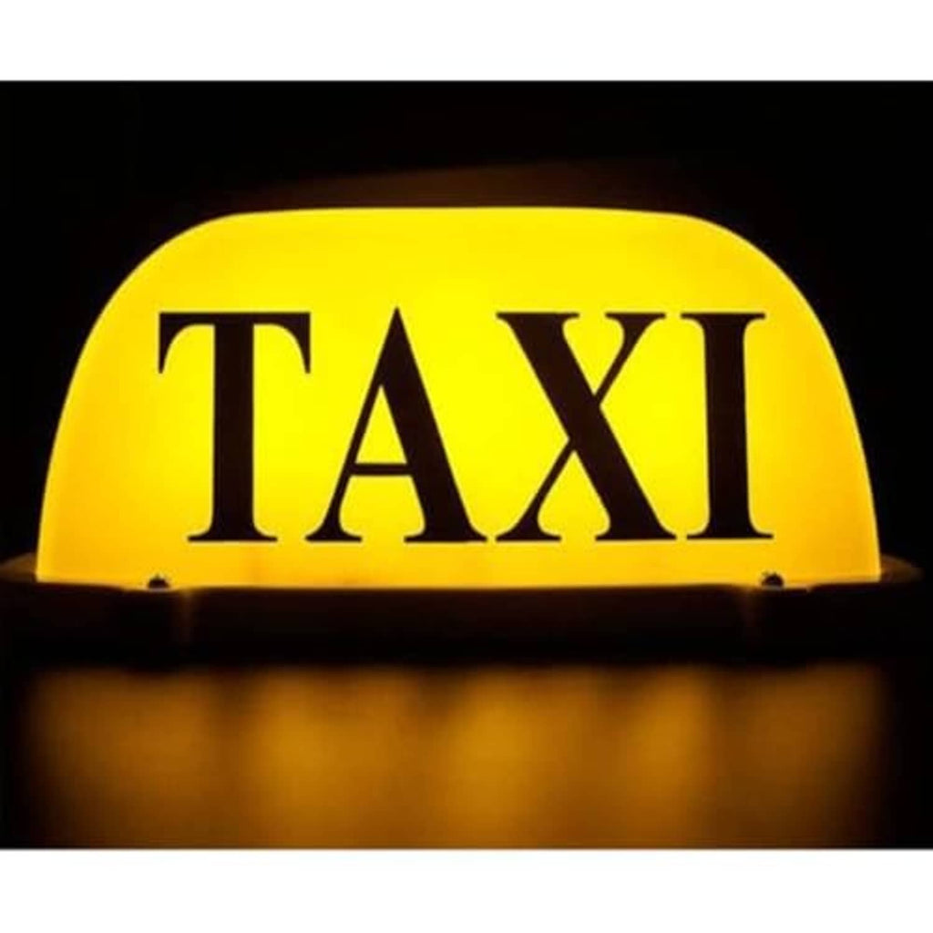 Illuminated yellow TAXI dome LED car sign light with dark base glowing at night