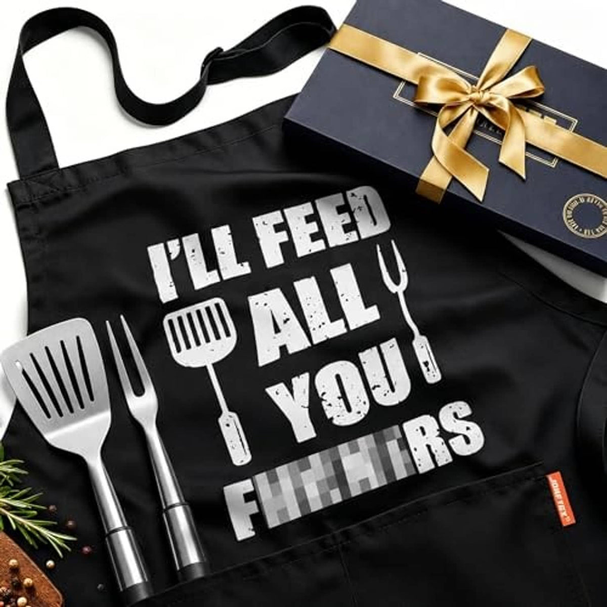 Black cooking apron with 'I'll feed all you' slogan and utensil graphics