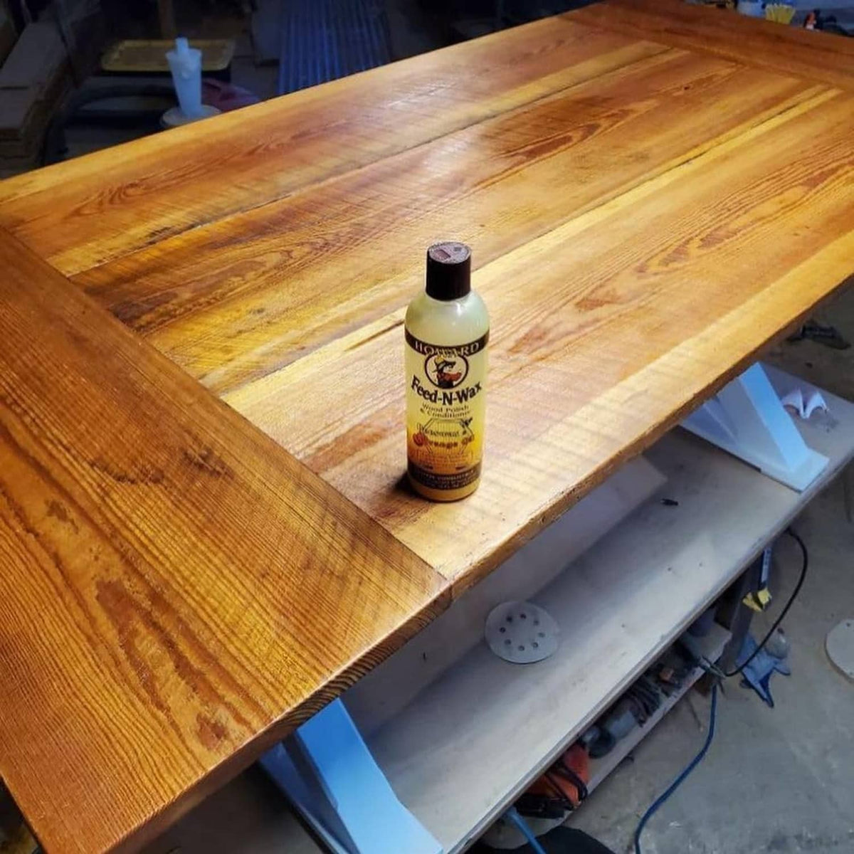 Howard Feed-N-Wax wood polish bottle on a wooden workbench