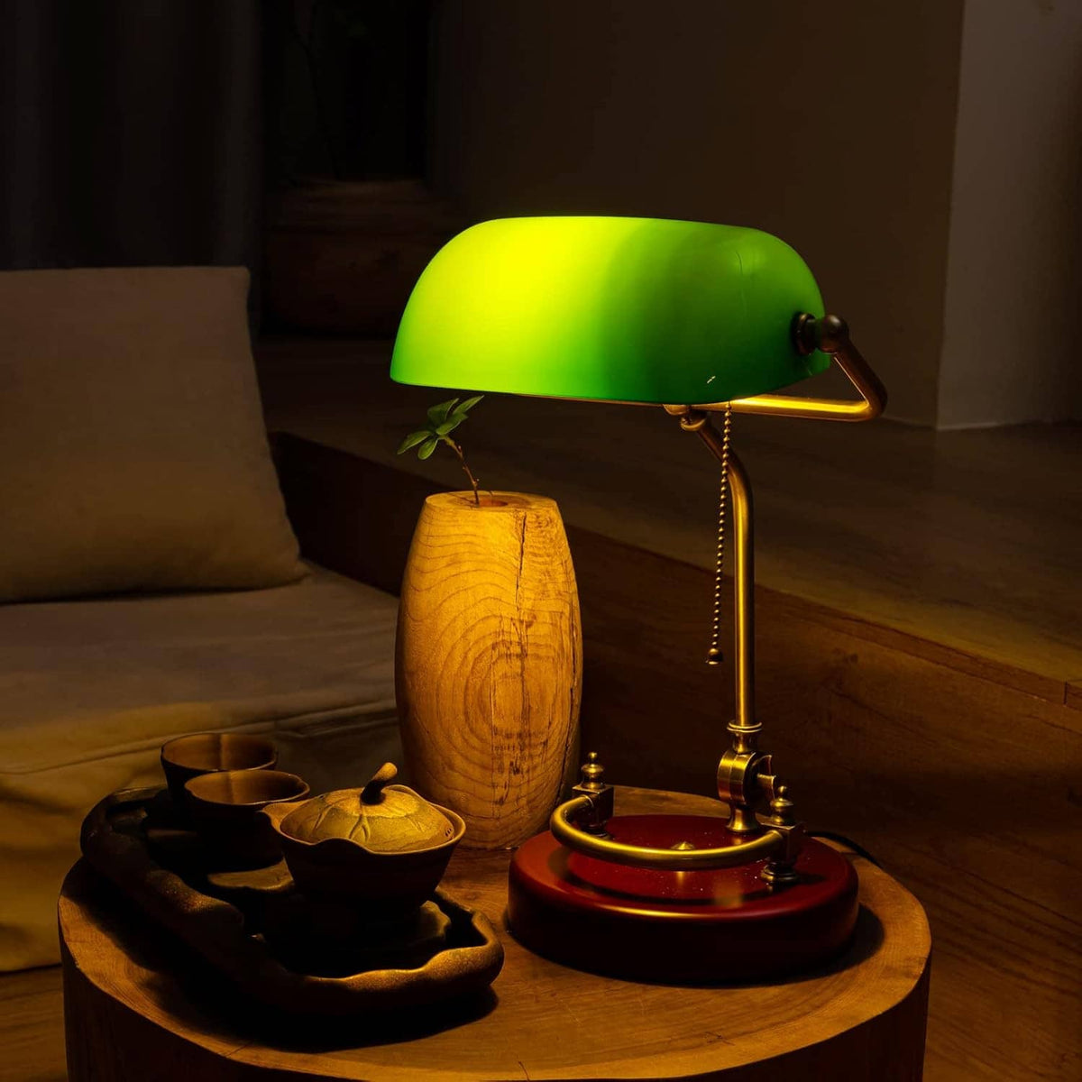 Glowing green bankers desk lamp with brass frame and round red wood base