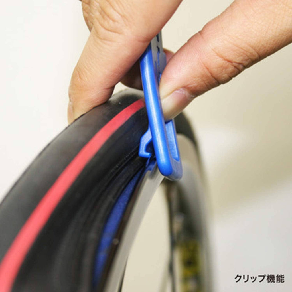 Blue tire lever being used on a bicycle tire edge with a hand