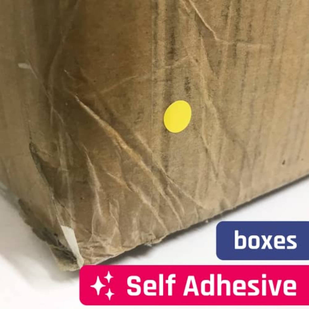 Self-adhesive yellow round dot sticker applied on a cardboard surface
