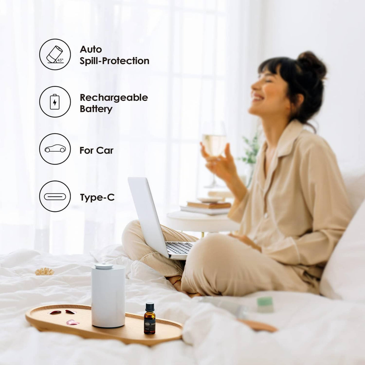 White waterless essential oil diffuser on a bed beside an amber oil bottle