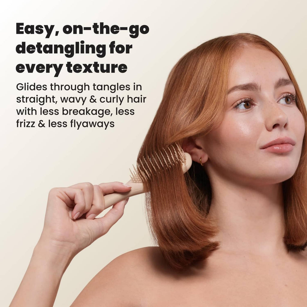 Mini detangling hair brush held while brushing auburn hair