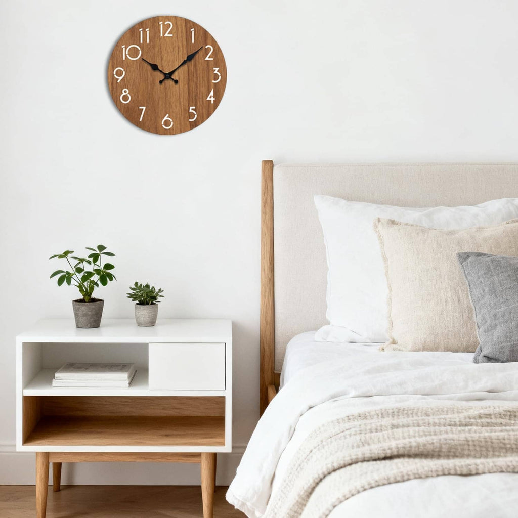 Small round wooden wall clock with white numerals and black hands on a light wall