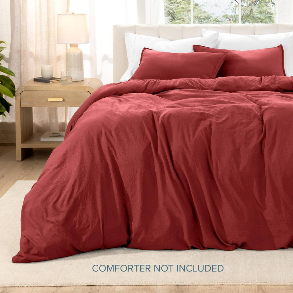 Red duvet cover set with two pillow shams, draped over a bed