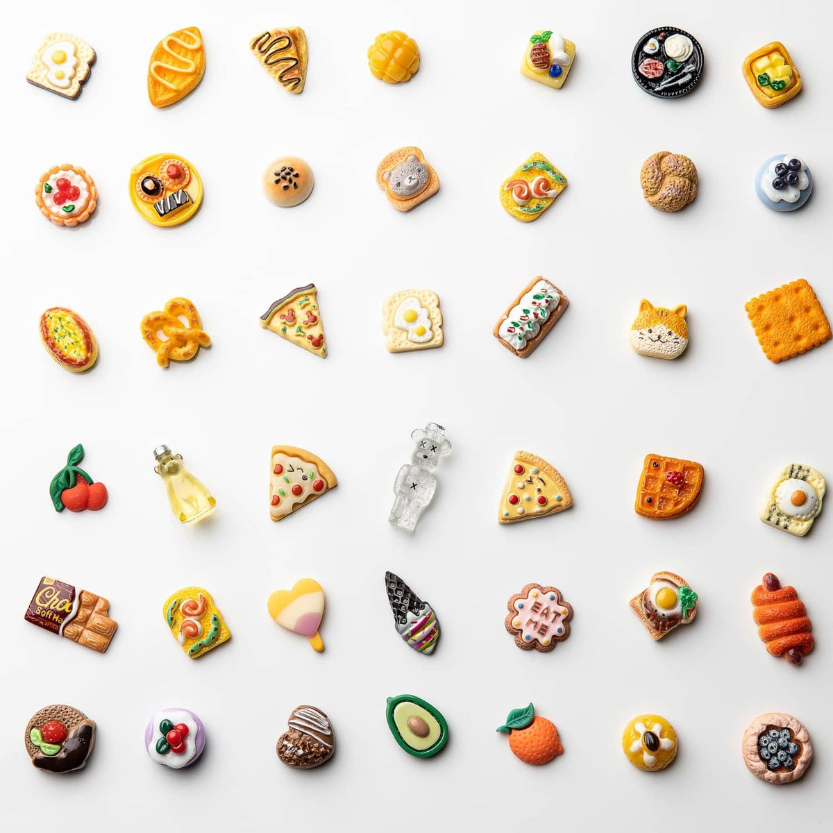 Assorted resin food charm set scattered on flat layout: pizzas, hearts, cookies, fruit, and more