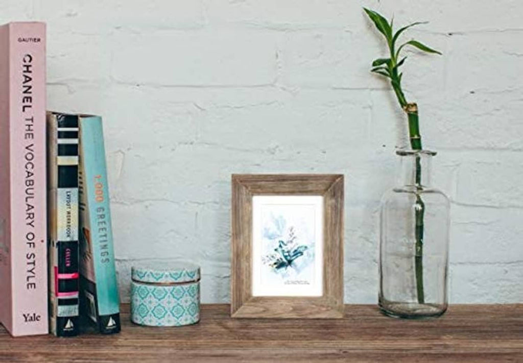Brown solid wood 5x7 picture frame on a tabletop with a framed print