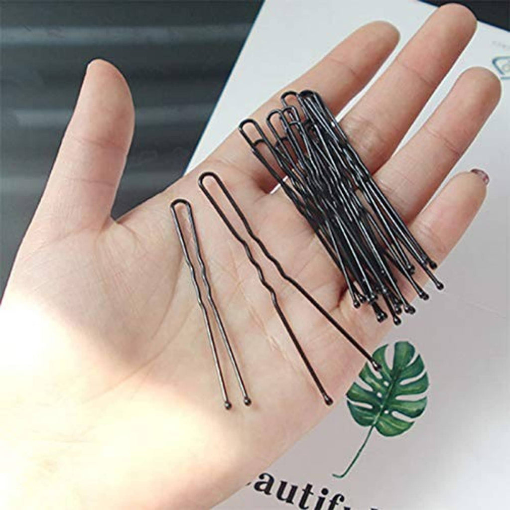 Black U-shaped bun hair pins held in hand, multiple pins