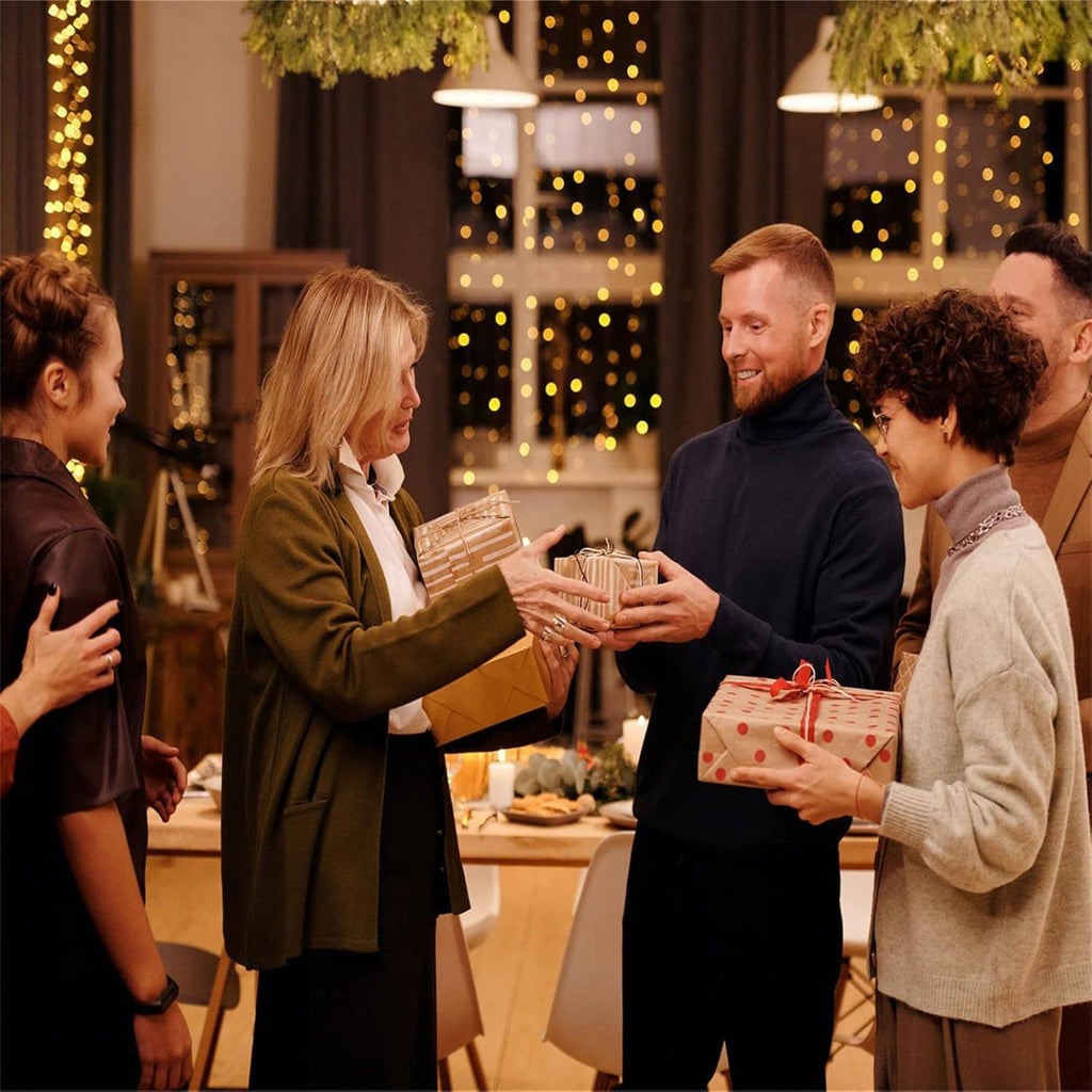 People exchanging wrapped gifts at a decorated event table