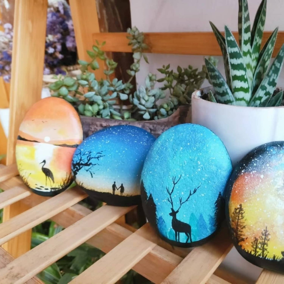Set of painted oval river rocks with blue night sky and deer silhouette designs