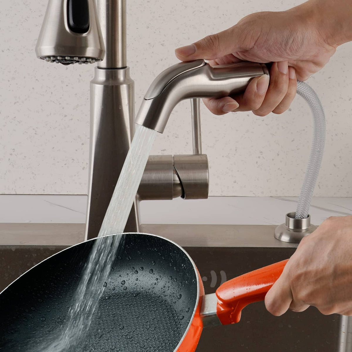 Brushed nickel faucet sprayer attachment spraying a water stream into the sink
