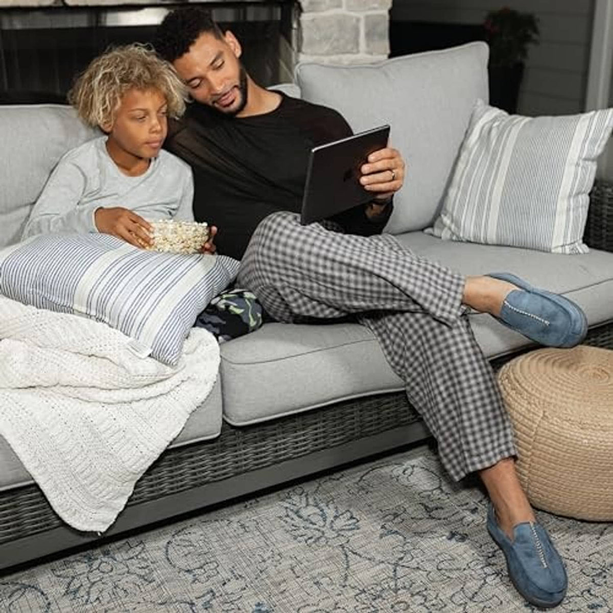 Blue microsuede moccasin slippers worn by adult on sofa