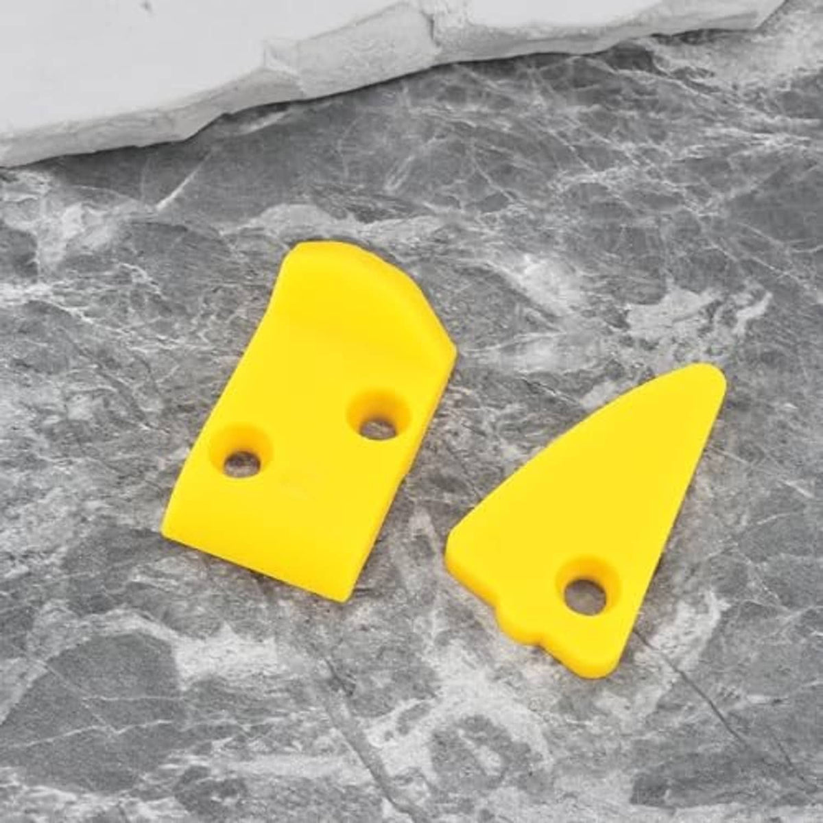 Yellow plastic tire changer inserts with mounting holes, two pieces on gray