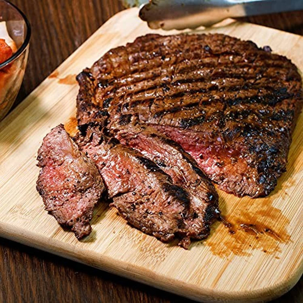 Grilled steak with dark Montreal-style seasoning rub on a wooden board