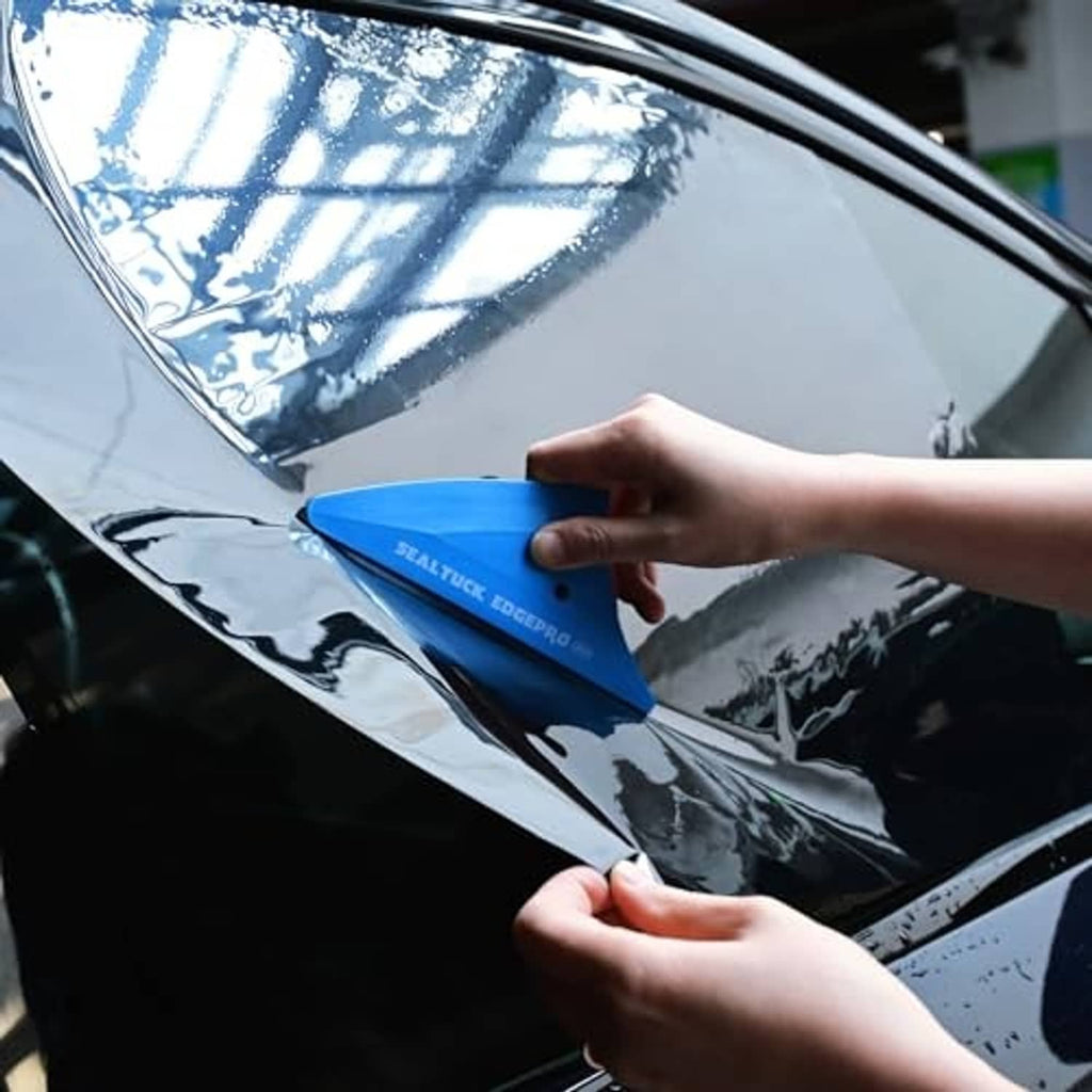 Hand using blue triangle window tint squeegee on car window film