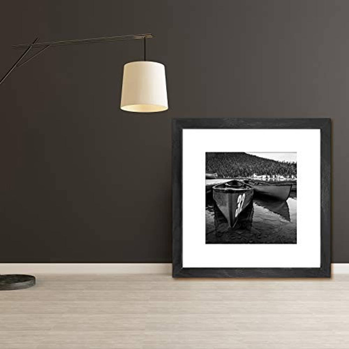 Black 12x12 picture frame with white mat on a floor against a wall.