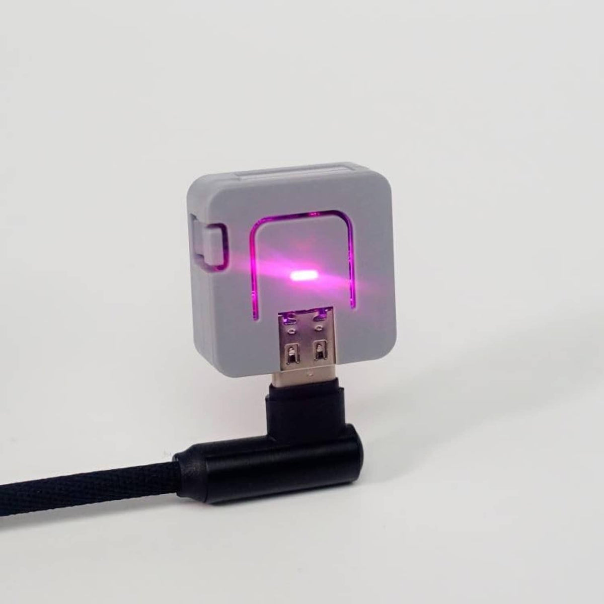 Grey ATOM Lite ESP32 module with magenta status light through front window